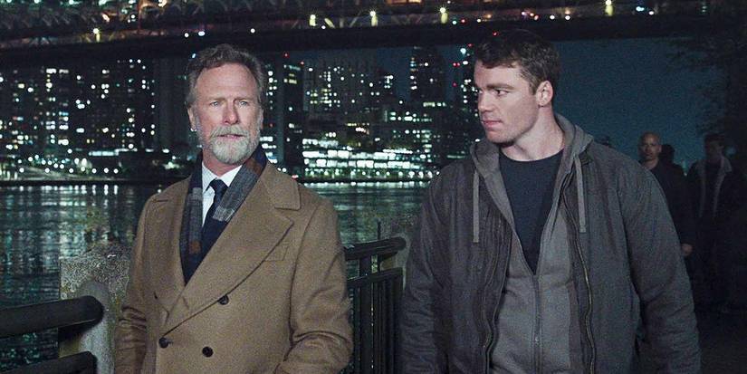Louis Herthum (Jacob Monroe) and Gabriel Basso (Peter Sutherland) walking with the city in the background in The Night Agent