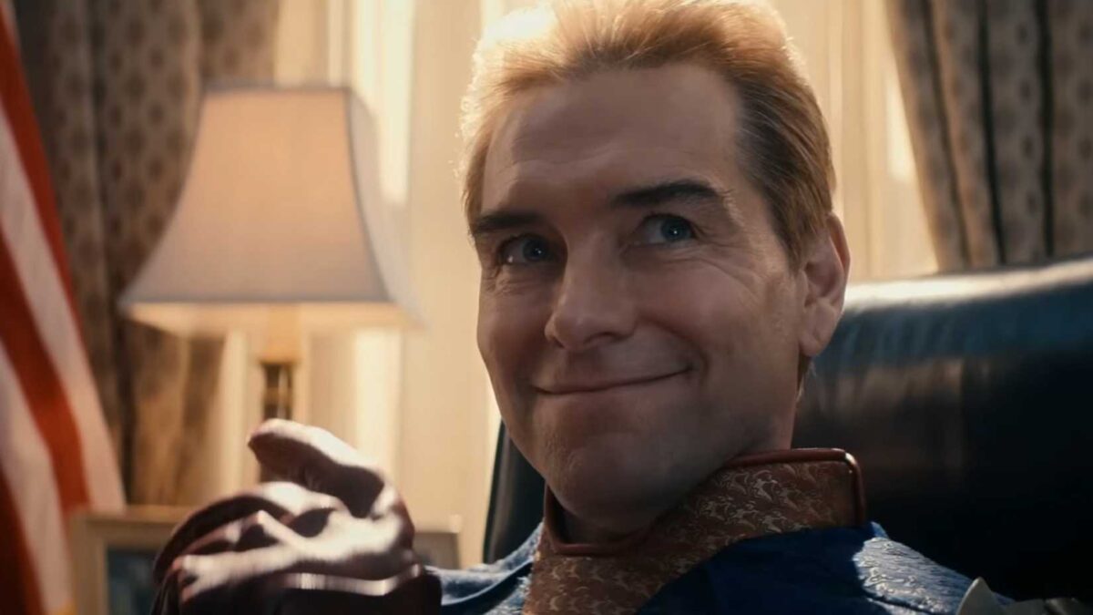 Homelander smiles while sitting at the Resolute Desk in the Oval Office in The Boys season 4(2)