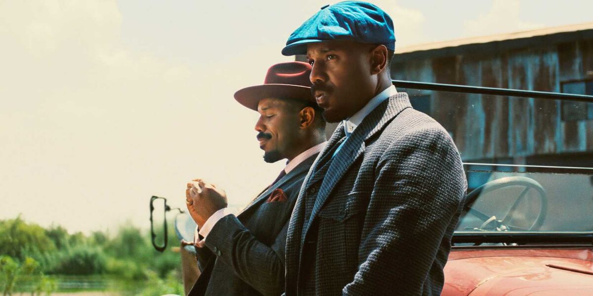 Michael B. Jordan as Smoke and Stack leaning against a car in Sinners