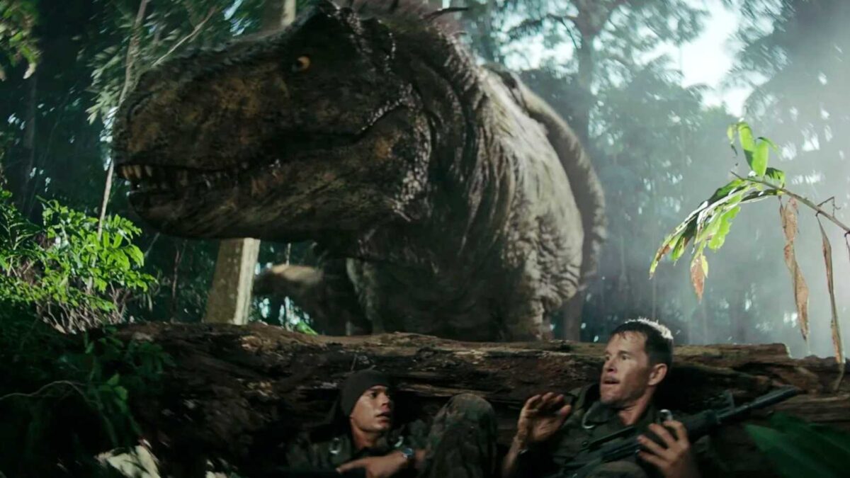 Two soldiers hiding behind a fallen tree with a T-Rex above them in Primitive War